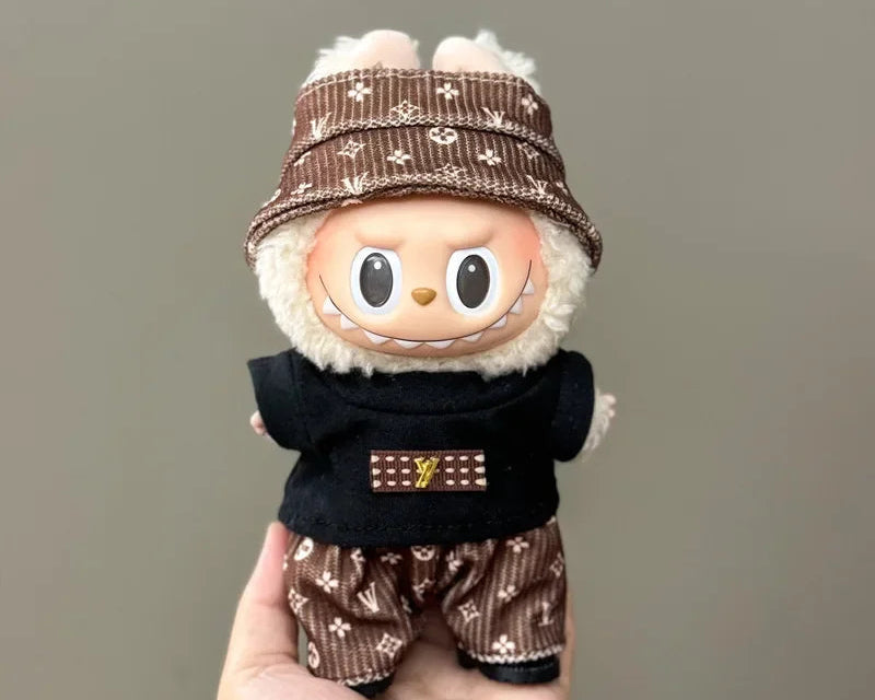 Stuffed toy with a brown hat and black outfit held in a hand against a gray background